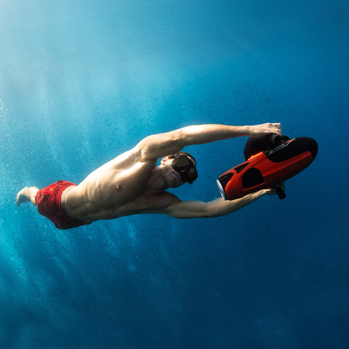 Swimmer holding a red Sublue VAPOR underwater scooter