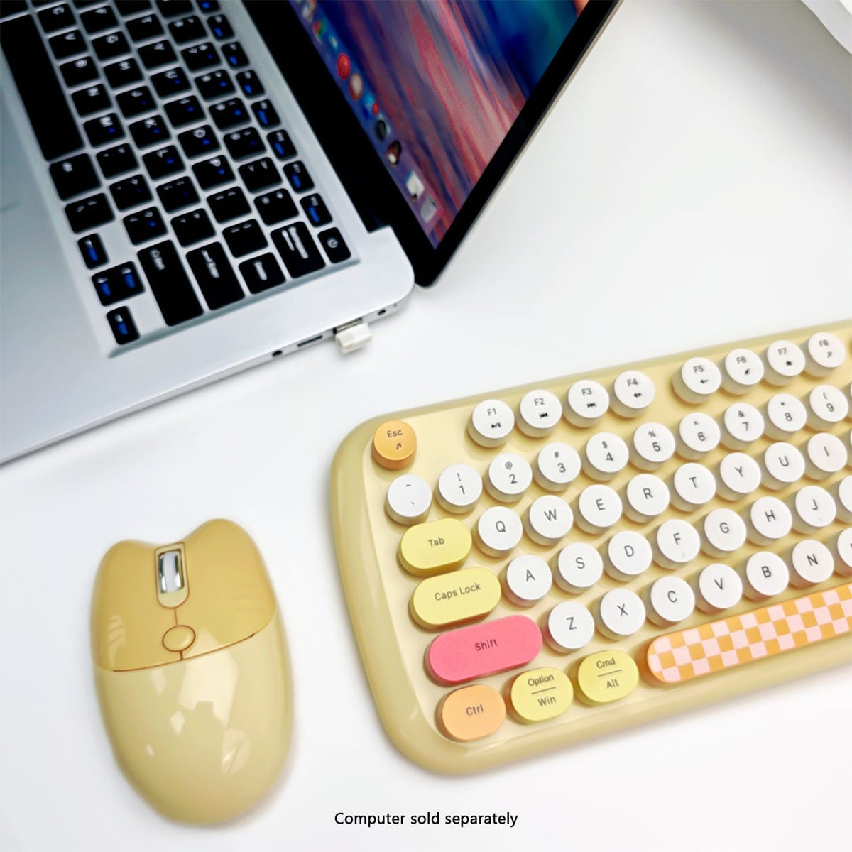 Yellow KB13 mouse and rounded keys beside a laptop