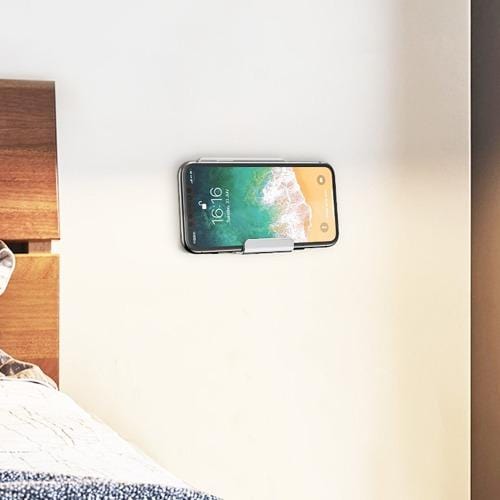 Silver wall mount holding a phone beside a bed