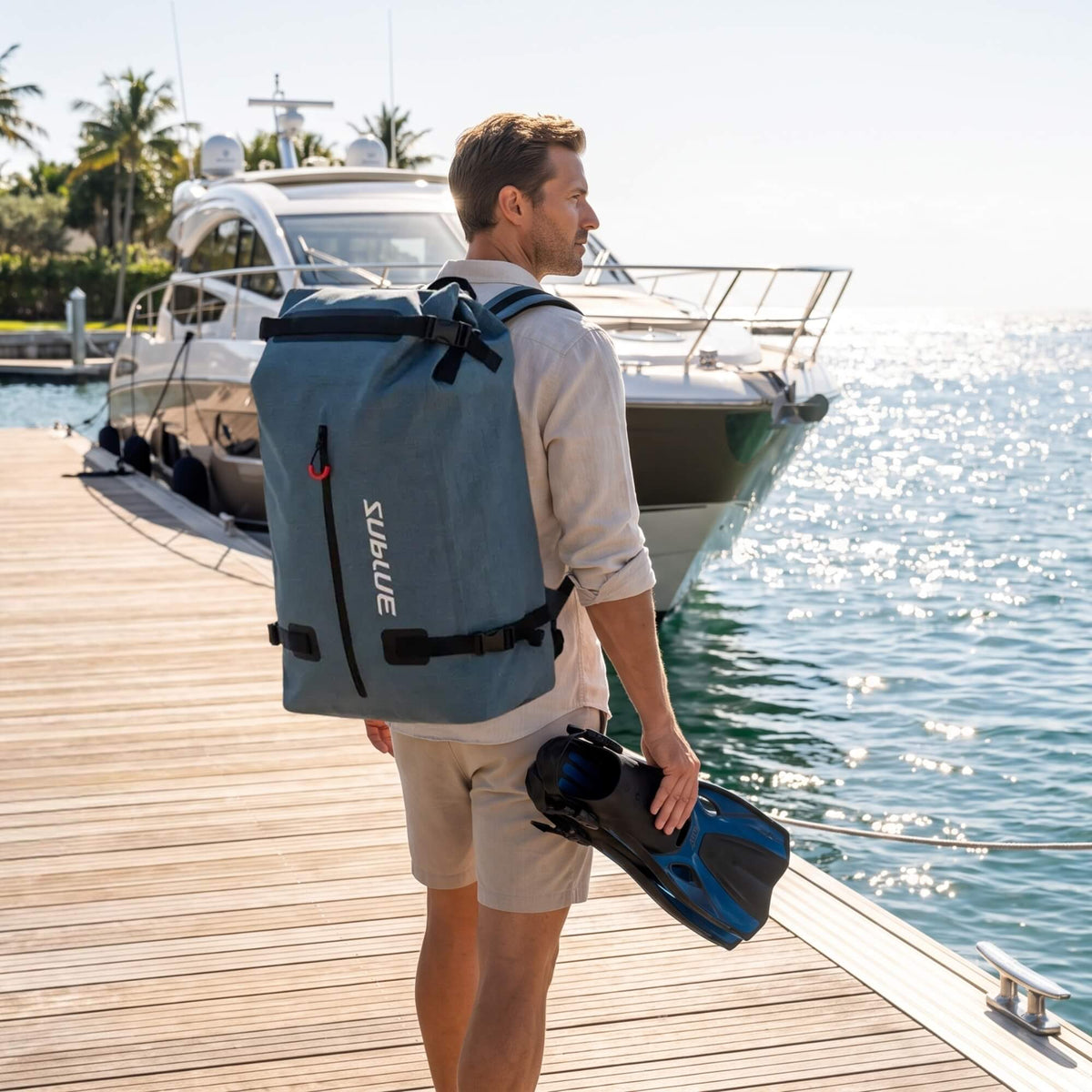 Person carrying a Sublue 52L waterproof backpack beside a boat