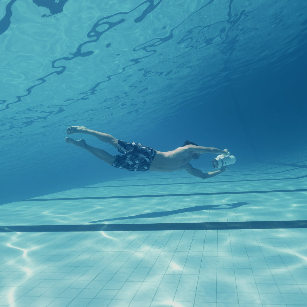 Swimmer using a Sublue EZ underwater scooter in a pool