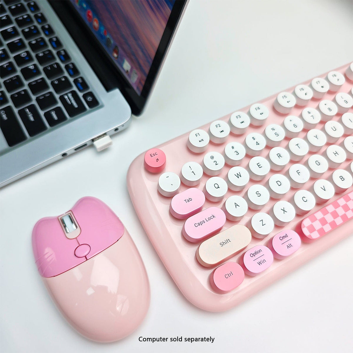 Pink KB10 mouse and rounded keys beside a laptop