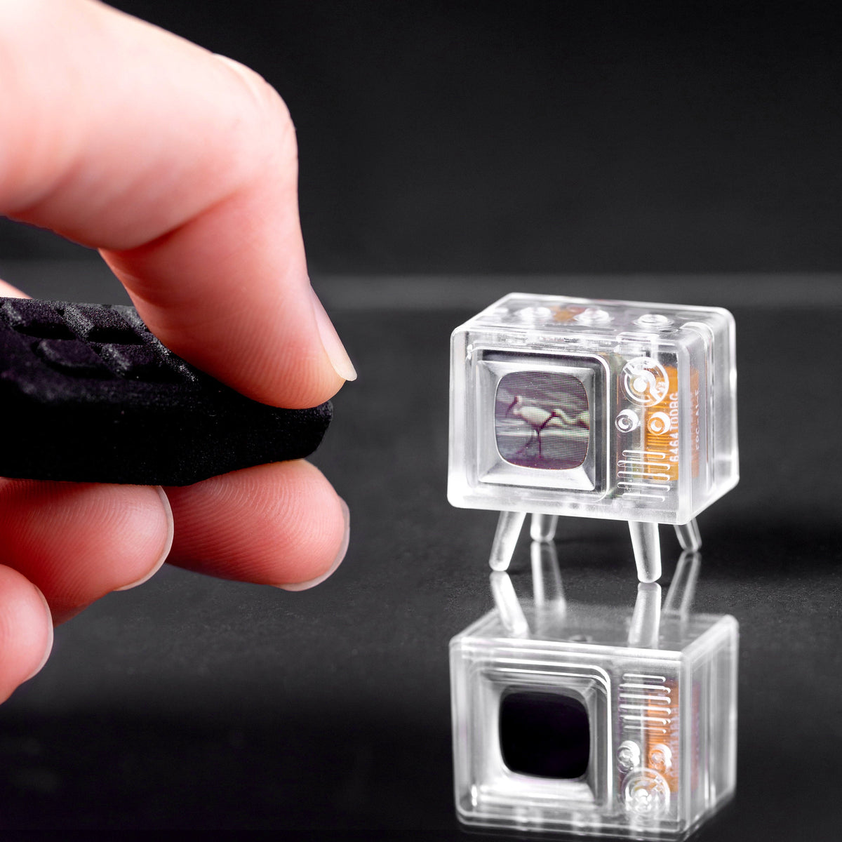 Clear TinyTV Mini playing video with infrared remote held nearby
