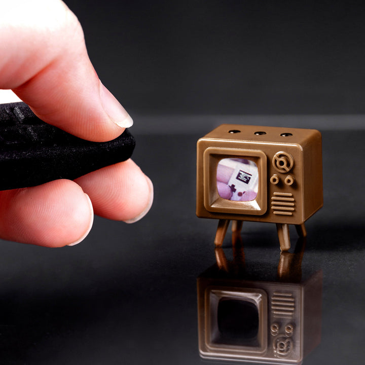 Brown TinyTV Mini playing video beside the Tiny Remote