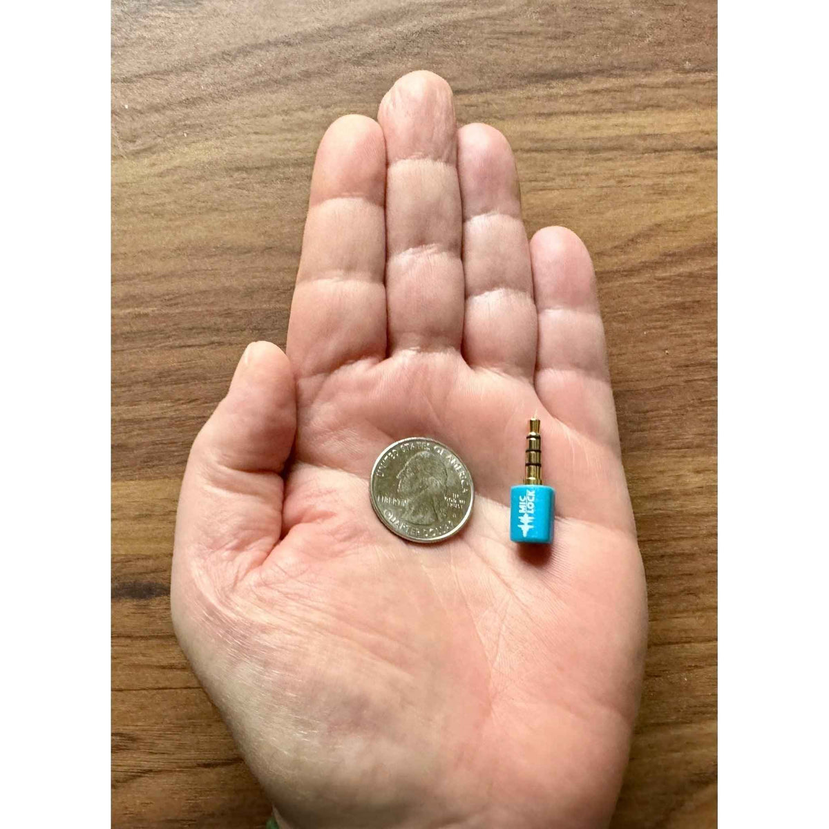 Mic-Lock Mini blocker in a hand beside a coin for scale