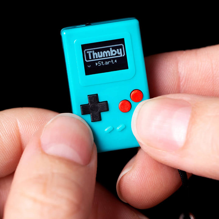 Teal Thumby keychain game console held between fingers